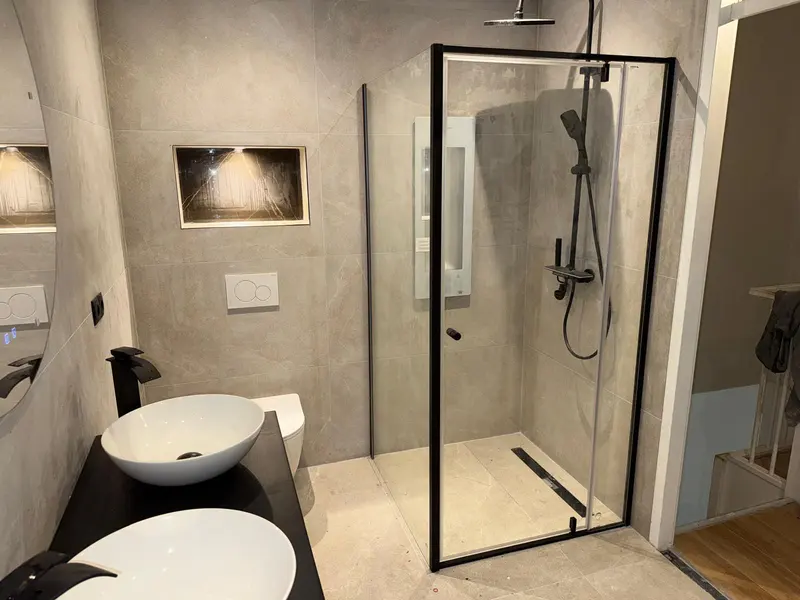 Badkamer met douchewand in zwart en betonlook tegels