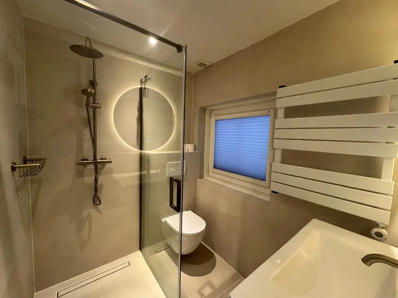 Badkamer met inloopdouche, ronde spiegel en witte designradiator