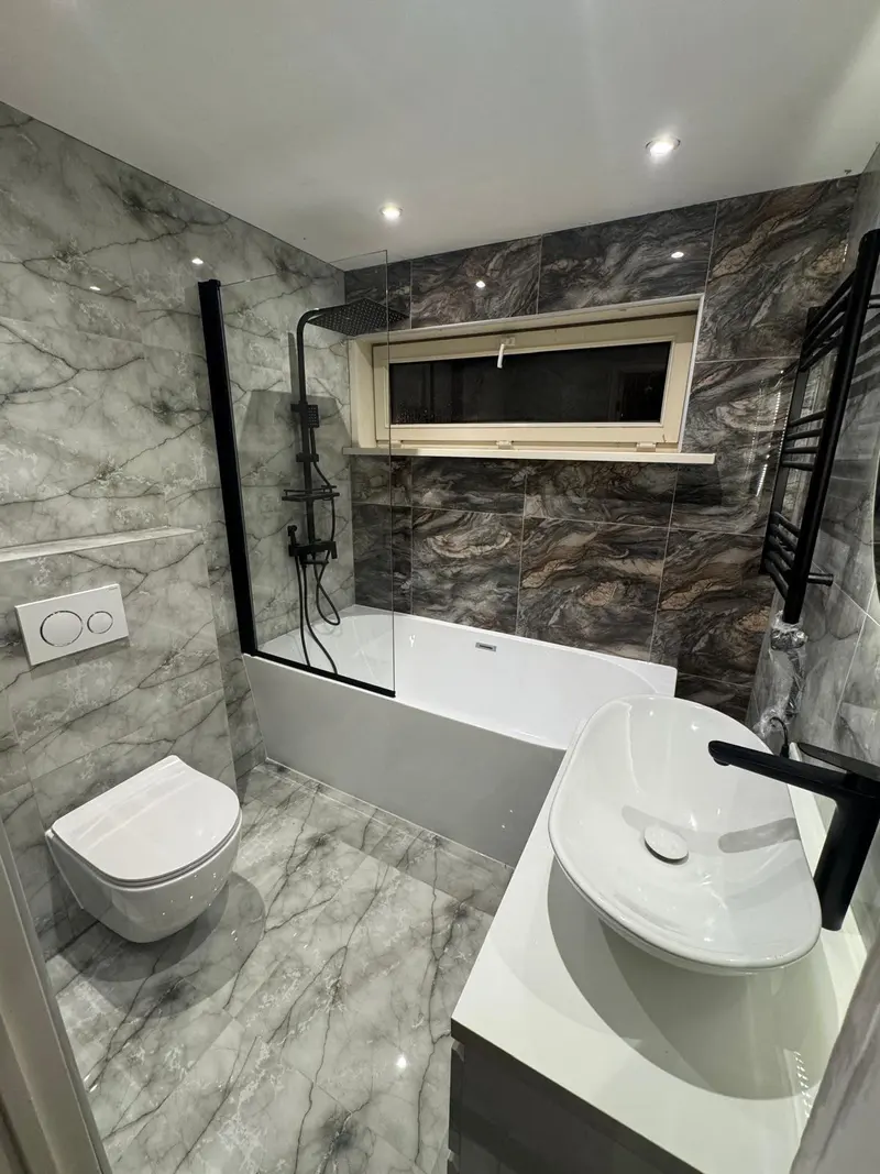 Badkamer met ligbad en natuursteenlook wandtegels
