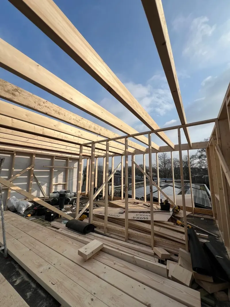 Dakopbouw in aanbouw in Rotterdam: houtskeletwanden met schoren en de nieuwe dakbalklaag op het bestaande platte dak