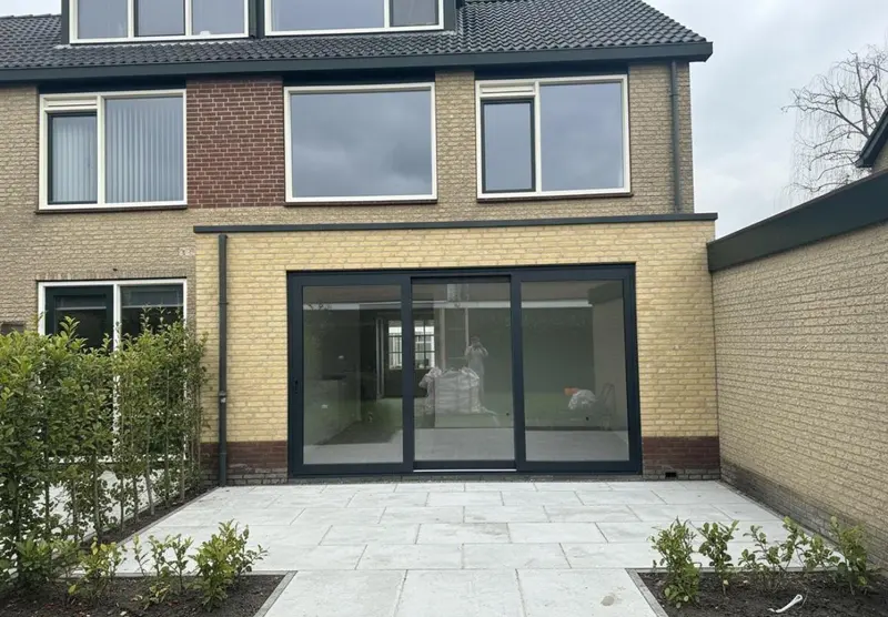 Uitbouw met schuifpui en aangelegd terras, gezien vanuit de tuin