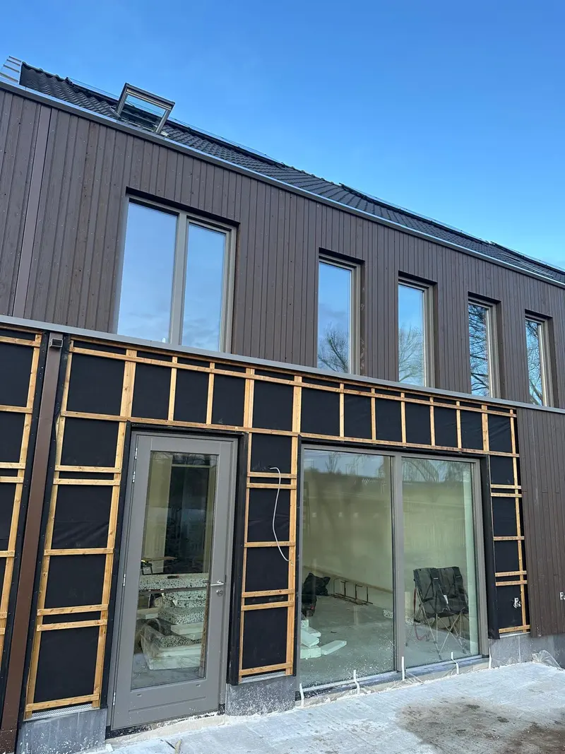 Houtskeletbouw uitbouw met donkere gevelbekleding en kozijnen tijdens de bouw
