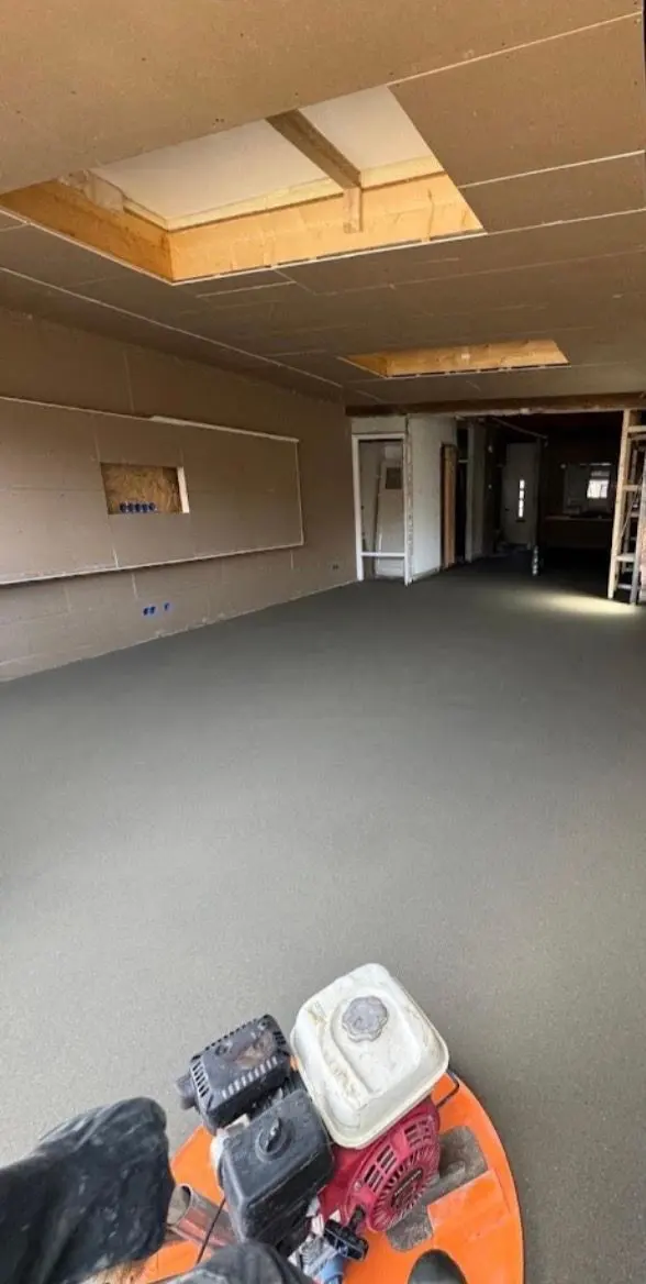 Dezelfde woning tijdens de uitvoering: de dekvloer is net gevlinderd en nog nat, het plafond staat in plaatmateriaal met de lichtkoven al uitgespaard, en de wanden staan in de ruwbouw met de elektradozen al op hun plek