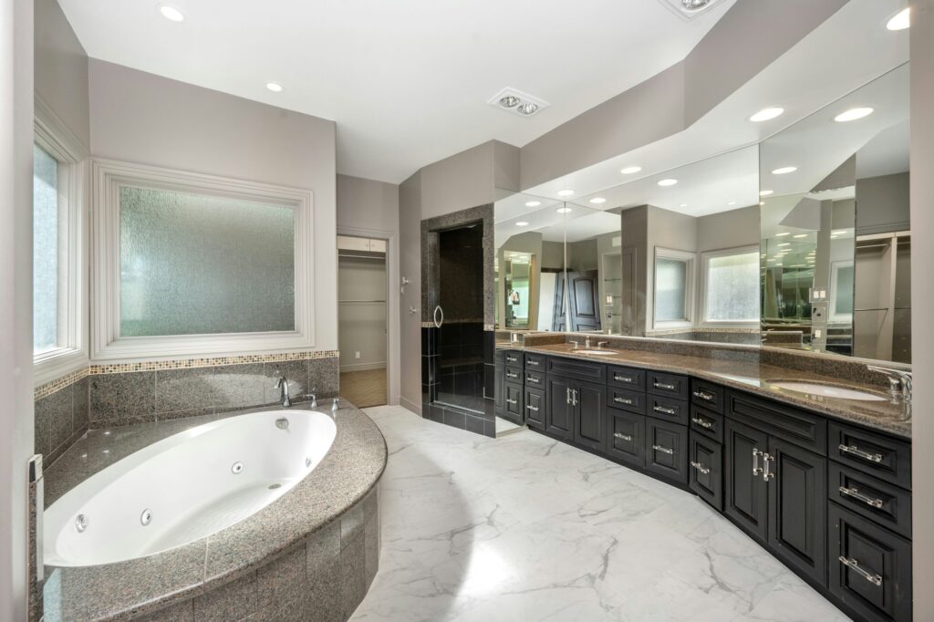 Spacious white and gray bathroom with jacuzzi tub by windows in Encino, California